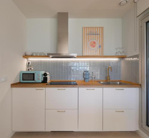 eine Küche mit weißen Schränken und einer Mikrowelle in der Unterkunft Apartamentos Lobamar in Gijón