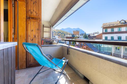 a blue chair sitting on a balcony with a view at Hostdomus - City Center Apartment in Sestriere
