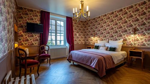 a bedroom with a bed and a chandelier at Le Prieuré d'Arbois in Arbois