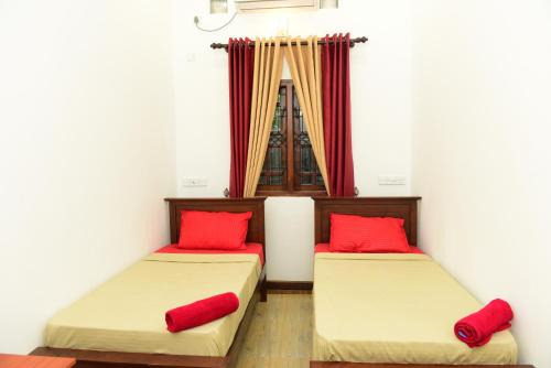two beds with red pillows in a room at Royal Beach Hotel in Trincomalee