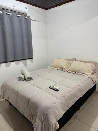 a large bed in a white room with a remote control on it at Apart Centro CDE in Ciudad del Este