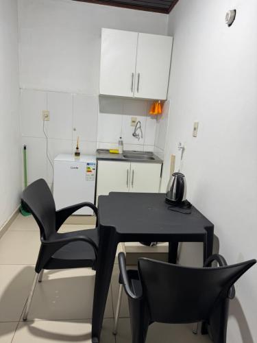 a black table and chairs in a kitchen with white cabinets at Apart Centro CDE in Ciudad del Este
