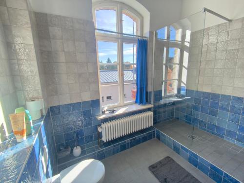 a blue tiled bathroom with a shower and a window at Zwei "Giebelwohnungen" im Kunstgut Krahne in Krahne
