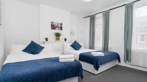 Russel Square Rooms في لندن: سريرين في غرفة باللون الأزرق والأبيض