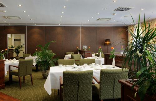 a restaurant with white tables and chairs and plants at VILA VITA Burghotel Dinklage in Dinklage