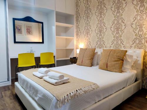 a bedroom with a white bed with two yellow chairs at Vintage Place - Azorean Guest House in Ponta Delgada