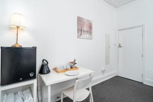 Russel Square Rooms في لندن: غرفة بها مكتب أبيض مع تلفزيون وكرسي