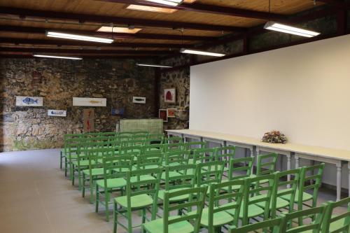 an empty room with green chairs and a white wall at Batteria Chiodo rifugio escursionistico e culturale in Monte Marcello