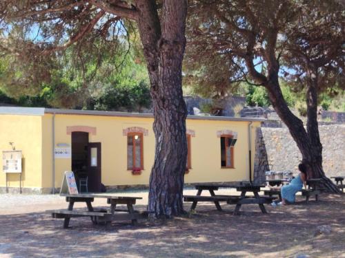 a group of picnic tables in front of a yellow building at Batteria Chiodo rifugio escursionistico e culturale in Monte Marcello