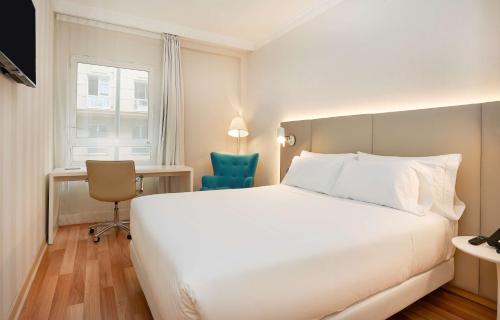 Una habitación de hotel con una gran cama blanca y una silla. en NH Bilbao Deusto, en Bilbao