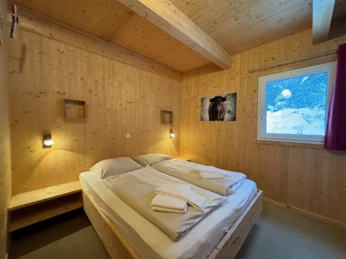 a bed in a wooden room with a window at Chalet Bastion in Brandstätter