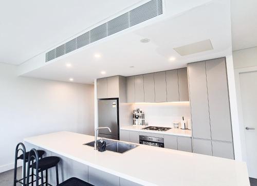 a white kitchen with a sink and a counter at Timeless Black n White Charm 2BR w Kids room in Sydney