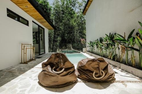 two bags are sitting next to a swimming pool at Villas Tamu 4 in Bingin Beach