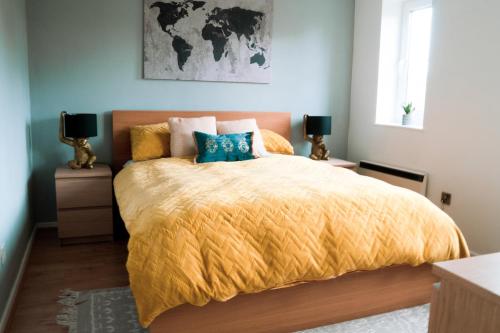 a bedroom with a bed with a yellow comforter at Modern flat in Cardiff Bay in Cardiff