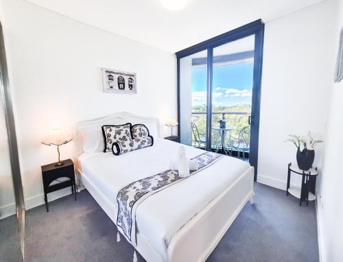 a white bedroom with a bed and a large window at Timeless Black n White Charm 2BR w Kids room in Sydney