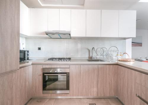 a kitchen with white cabinets and a stainless steel oven at Free housekeeping visits during your stay - StayShort - Dubai South 1BR sleeps 4 in Dubai Marina