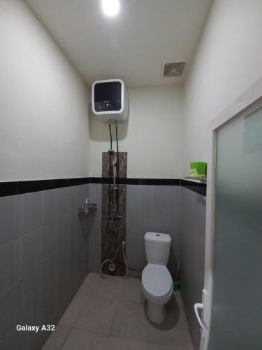 a bathroom with a toilet and a tv on the wall at NARAYA Guest House in Mataram