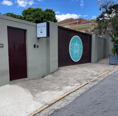 a fence with a door and a sign on it at Café e Pousada Jardim Secreto in Santa Rita do Sapucaí