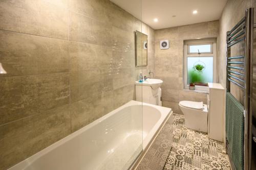 a bathroom with a tub and a toilet and a sink at James Terrace by STAE Homes in Porth