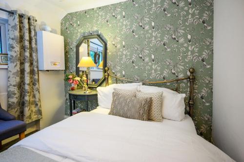 a bedroom with a bed and a wall with bird wallpaper at James Terrace by STAE Homes in Porth