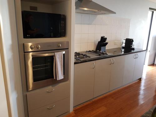 a kitchen with an oven with a microwave above it at Sandy Toes and Sunsets Beach House in Bunbury