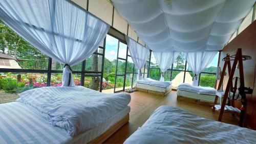 a bedroom with two beds and large windows at Hương Lúa Homestay Măng Đen in Kon Plong