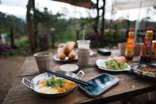 a wooden table with plates of food on it at Hương Lúa Homestay Măng Đen in Kon Plong