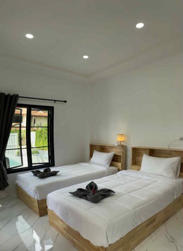 two beds in a white room with a window at Villa Mokara Brassia 2 bedrooms by orchids pool villas in Ko Lanta