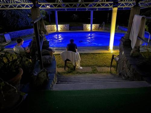 a group of people sitting by a pool at night at Manor House on the Danube Bend in Tahitótfalu