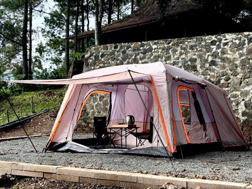 a tent sitting next to a stone wall at KAIA Camp by Kalimaya in Cicadas