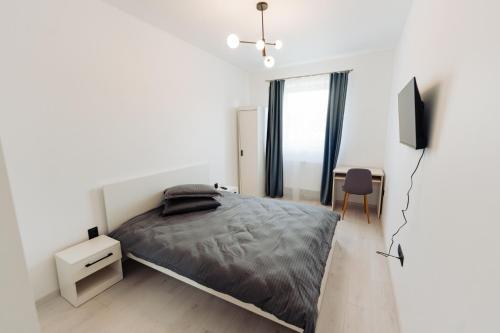 Un dormitorio blanco con una cama y un televisor. en Cozy 2-Room Apartment - Free Parking - Close to Airport, en Apahida