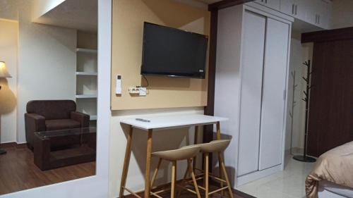 a room with a table and two stools and a television at Ruby Apartment #29 in Yogyakarta