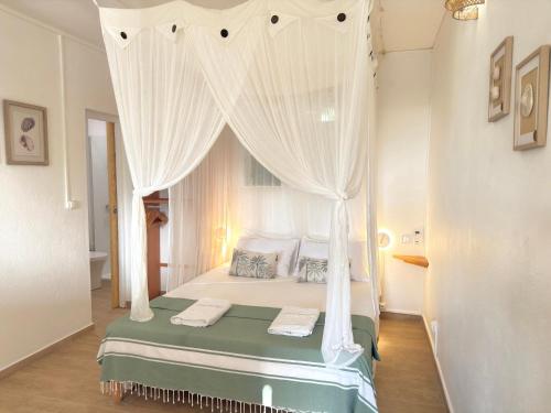 a bedroom with a canopy bed with a window at La p’tite barque Antillaise in Deshaies