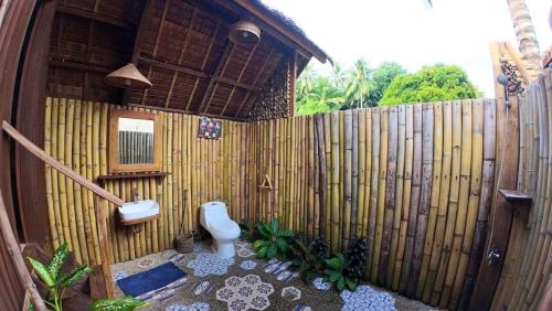 a bathroom with a toilet and a wooden fence at Playa Encantada Beach Resort in El Nido