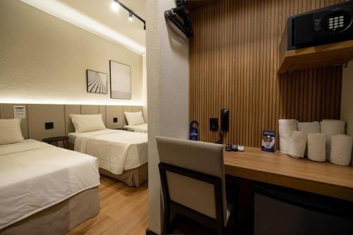 um quarto de hotel com duas camas e uma escrivaninha com televisão em Morada Inn Hotel em Franca