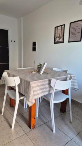 a wooden table with two white chairs and a laptop on it at VitruApart Temporario in Resistencia
