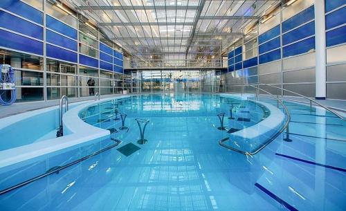a large swimming pool with blue water in a building at Gite tafan in Pouillon