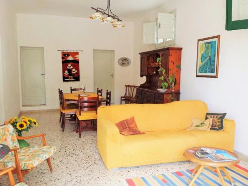 sala de estar con sofá amarillo y mesa en Appartamento La Pinetina en Valderice