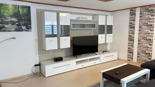 a living room with a tv and a white entertainment center at LembergLodge Gosheim in Gosheim