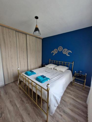 une chambre avec un lit avec un mur bleu dans l'établissement Cosy la Riveraine Cottage, à Saint-Aignan