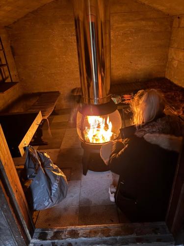 Eine Frau sitzt vor einem Kamin in der Unterkunft Suuri talo Kaskisaaressa lähellä Helsingin keskustaa in Helsinki