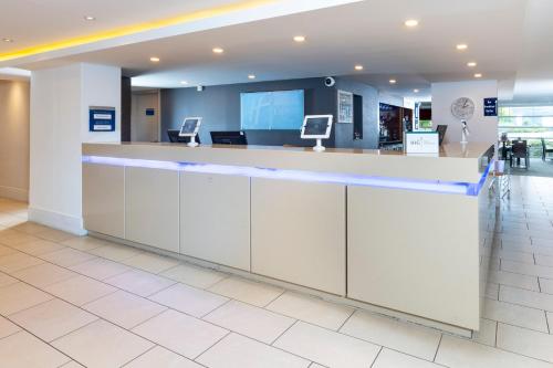 a reception counter in an airport with blue lights at Holiday Inn Express Milton Keynes by IHG in Milton Keynes