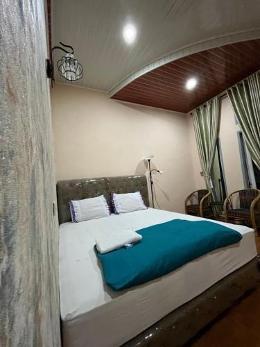 a bedroom with a large bed with a blue blanket at Sapo Guest House in Berastagi