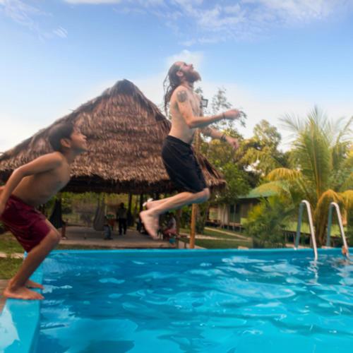 two young men jumping into a swimming pool at Maniti Eco-Lodge in Francisco de Orellana