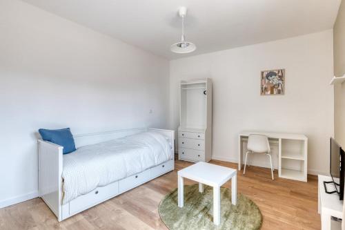 a white bedroom with a bed and a chair at Green 3 - Roubaix Gare in Roubaix