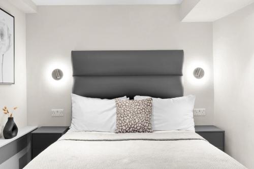 a white bedroom with a large bed with white pillows at Cleveland Residences Kensington in London