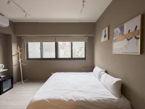 een slaapkamer met een wit bed en een raam bij meimo文旅 in Taichung