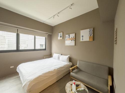 een slaapkamer met een bed en een stoel bij meimo文旅 in Taichung