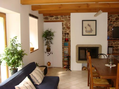 een woonkamer met een bank, een tafel en een open haard bij Maison Les Volets Bleus Binic in Lantic