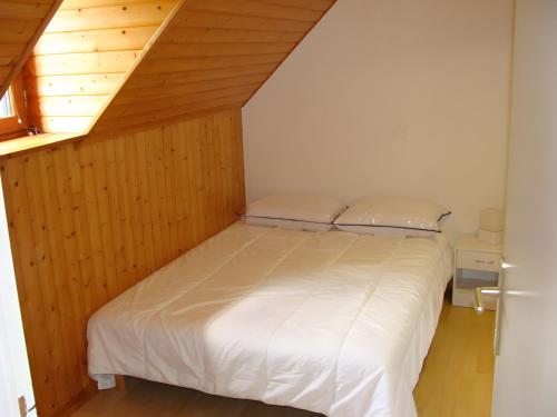 een slaapkamer met een wit bed met een houten wand bij Maison Les Volets Bleus Binic in Lantic